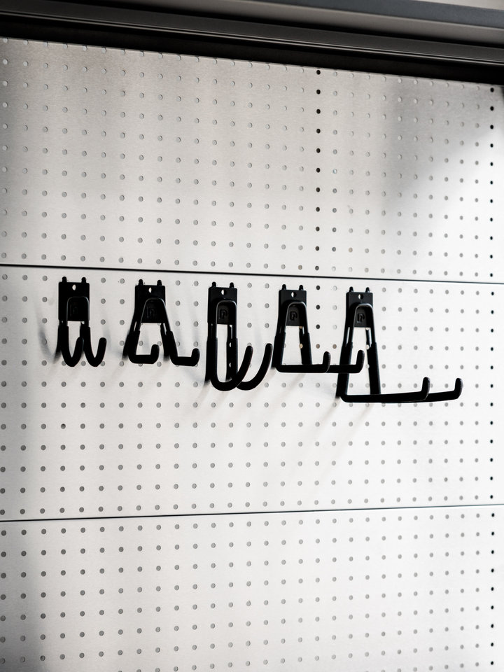 A row of black storage hooks displayed across a silver PegGrid panel.