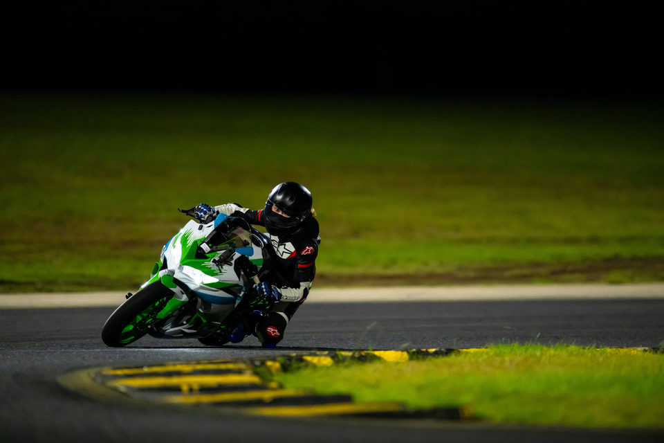 A green sports motorcycle and rider low over a yellow race-track kerb
